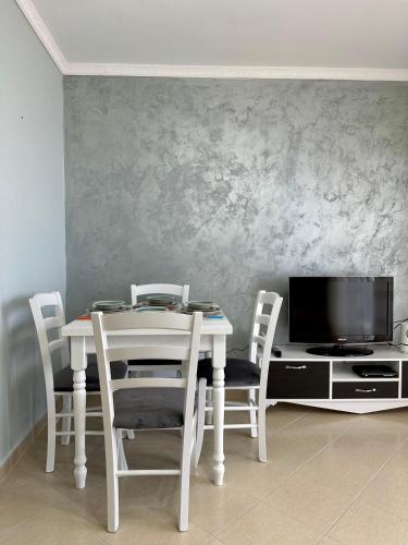 a dining room table with chairs and a tv at Apartment for rent Piqeras, Sarande in Piqeras