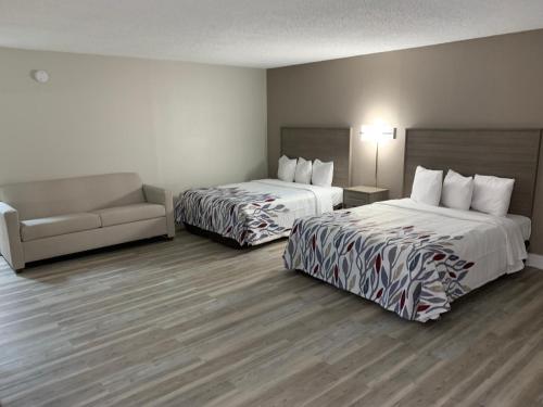 a hotel room with two beds and a couch at Red Roof Inn & Suites Vineland - Buena in Buena