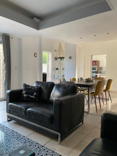 un canapé en cuir noir dans un salon avec une table dans l'établissement Maison de ville, spacieuse et cosy, à Montélimar