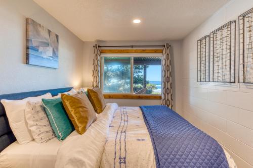 a bedroom with a bed with pillows and a window at Cape Cod Cottages - Unit 8 in Waldport