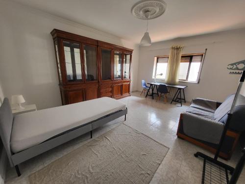 a bedroom with a bed and a couch and a table at Margem Sul rooms in Caparica