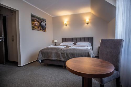 a bedroom with a bed and a wooden table at Nad Zatoką in Bryzgiel