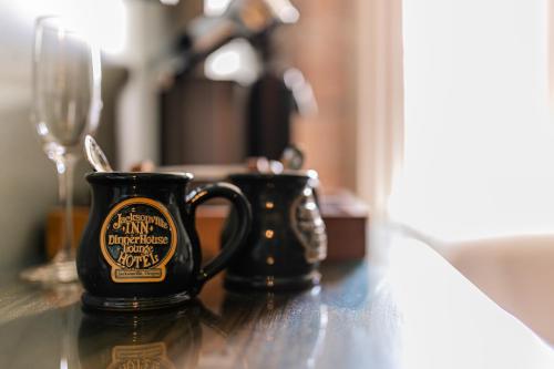 a black coffee mug sitting on a table with a glass at Historic Jacksonville Inn in Jacksonville