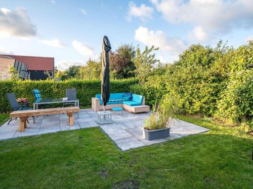 a patio with a bench and an umbrella at Chalet in Oostkapelle near the Beach in Oostkapelle