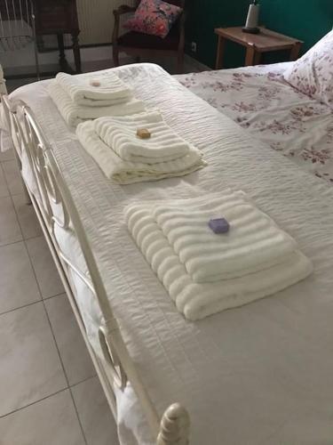 trois serviettes blanches sur un lit blanc dans une chambre dans l'établissement Villa calme grand jardin bord de mer. Parking, à Marseille