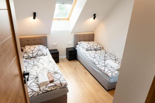 twee bedden in een kleine kamer met een raam bij Ginger Apartament in Wilkasy