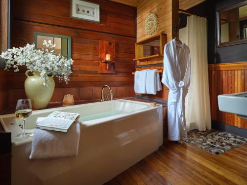 a bathroom with a tub and a vase of flowers at Abbey's Lantern Hill Inn in Ledyard Center