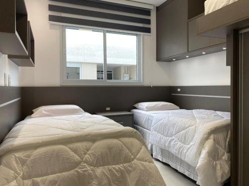 2 camas en una habitación con ventana en Apto de alto padrão em cond. nos Ingleses CCI210, en Florianópolis