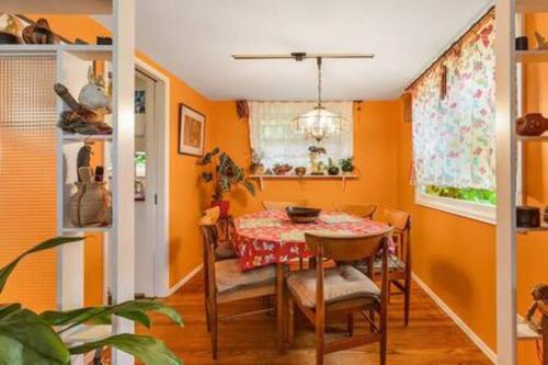 a dining room with orange walls and a table and chairs at Boho Bliss Bungalow in Shoreline
