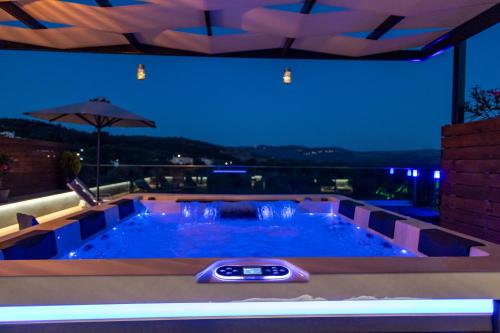 uma piscina no meio de um edifício à noite em Villa Paris with Rooftop & Jacuzzi em Valsamónero