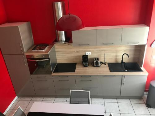 Elle comprend une petite cuisine avec des placards blancs et un mur rouge. dans l'établissement Neuville secrete, à Dieppe