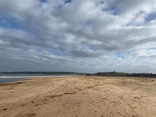 a sandy beach with a cloudy sky and the ocean at Applestow Cottage in Northam