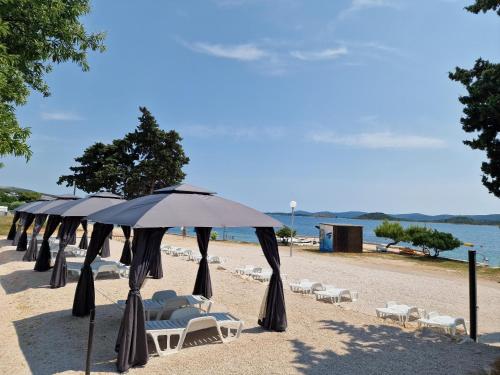 a row of umbrellas and chairs on a beach at 5 meters FROM THE SEA with private beach - 70m2 Colibri Sunset Apartments in Sveti Petar