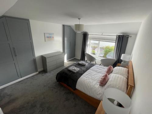 a bedroom with a bed and two chairs and a window at Leerick Cottage in Conwy