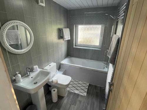 a bathroom with a sink and a tub and a toilet at Leerick Cottage in Conwy