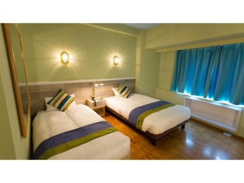 a room with two beds and a window with blue curtains at Hotel AreaOne Sakaiminato Marina - Vacation STAY 09680v in Sakaiminato