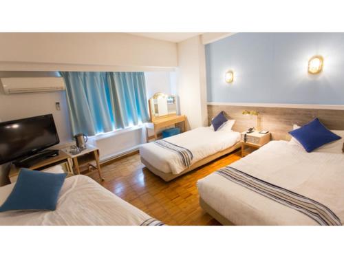 Hotel AreaOne Sakaiminato Marina - Vacation STAY 09684v في ساكايميناتو: غرفة فندقية بسريرين وتلفزيون بشاشة مسطحة