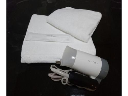 um secador de cabelo ao lado de uma pilha de toalhas brancas em Kokusai Towns Inn - Vacation STAY 52707v em Naha