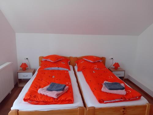 two beds in a room with red sheets and towels at Kötél utcai vendégház in Balatonkeresztúr