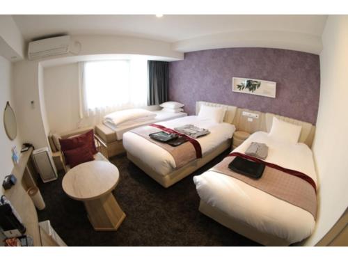 um quarto de hotel com três camas e uma mesa em Hotel Torifito Kashiwanoha - Vacation STAY 75947v em Kashiwa