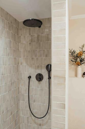 a shower in a tiled bathroom with a shower head at Clemonte Hotel - Your Reception-less Boutique Hideaway in Salzburg