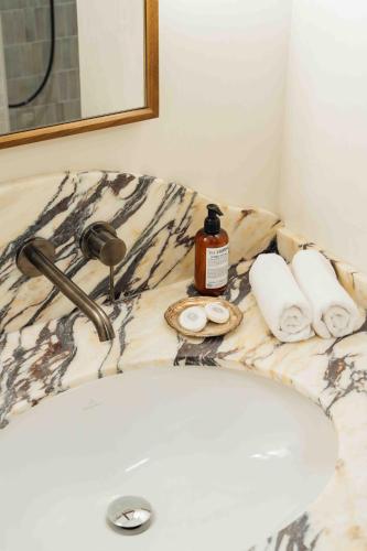 a bathroom sink with a bottle of soap and towels at Clemonte Hotel - Your Reception-less Boutique Hideaway in Salzburg