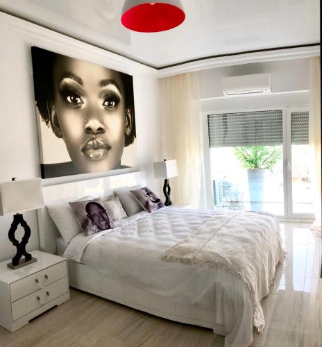 a white bedroom with a large poster of a woman at White Tower Mamaia - Private Apartment in Mamaia