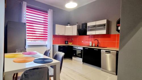 a kitchen with a table and a kitchen with red walls at Apartament Cumulus in Chojna