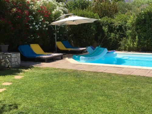 einen Pool mit Stühlen und einem Sonnenschirm in der Unterkunft Maison avec piscine et vue sur les collines. in Marseille