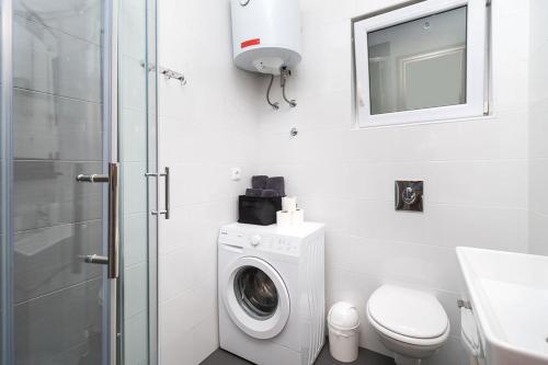 a bathroom with a washing machine and a toilet at Apartments Grubišić - Šibenik - parking included in Šibenik