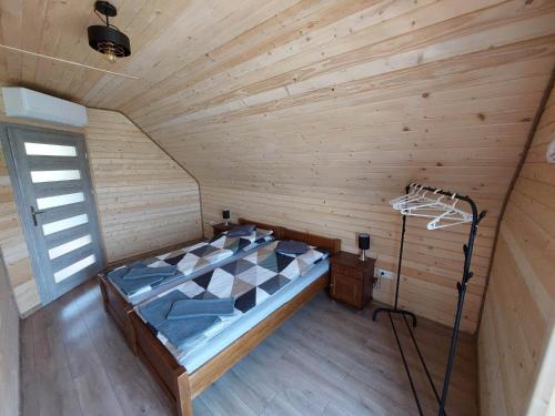 1 dormitorio con 1 cama en una habitación de madera en Domki na kocim zamku, en Grywałd