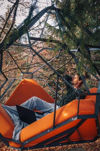 a man sitting on an orange object with a laptop at Armadillo Houses in Kopaonik
