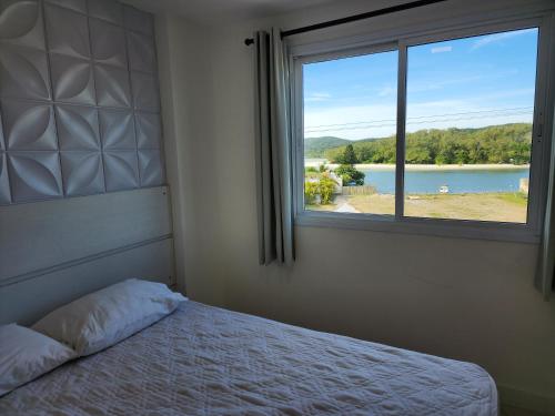 1 dormitorio con cama y ventana con vistas en PACIFIC - PRAIA DO FORTE, en Cabo Frío