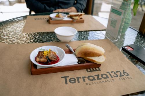 a table with a plate of food and a plate of bread at Palafito 1326 Hotel Boutique Chiloé in Castro