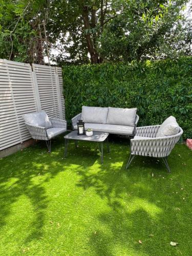 a garden with two chairs and a couch and a table at Beautiful 5-bedroom private house in quiet London street 2 minutes from station in London