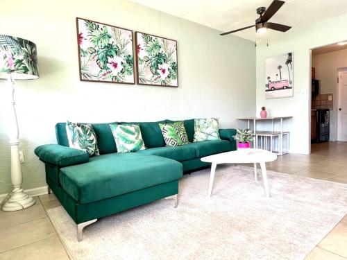 Palm Paradise in downtown Cocoa Beach في كوكاو بيتش: غرفة معيشة مع أريكة خضراء وطاولة