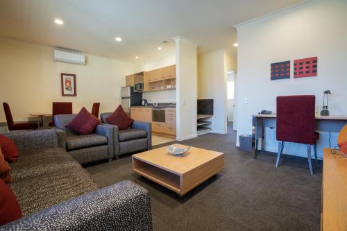 a living room with couches and a table and a kitchen at Regal Palms Resort in Rotorua