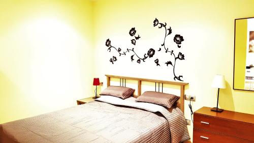 a bedroom with a bed with flowers on the wall at Lloret Beach Apartments in Lloret de Mar