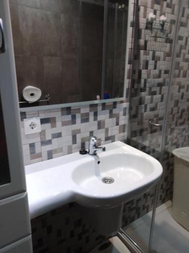 y baño con lavabo blanco y ducha. en Casa vacacional, en Porto do Son