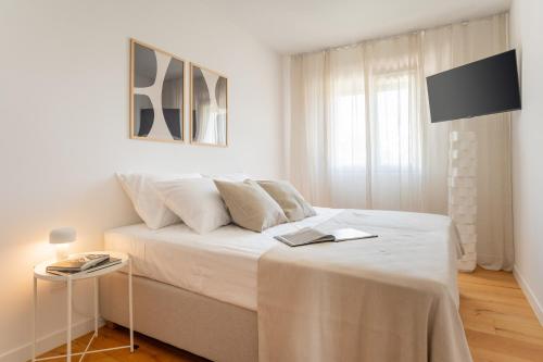 - une chambre blanche avec un lit et un livre dans l'établissement Villa Activitas - Professional Fitness & Pool, à Kaštela