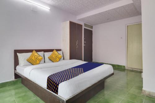 Schlafzimmer mit einem Bett mit gelben und blauen Kissen in der Unterkunft SPOT ON Apsara Hotel in Hyderabad