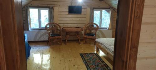 a room with a table and chairs in a cabin at Крайня Хата in Synevyrsʼka Polyana