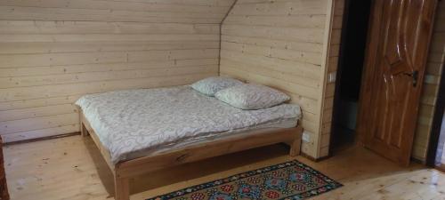 a small bed in a corner of a room at Крайня Хата in Synevyrsʼka Polyana
