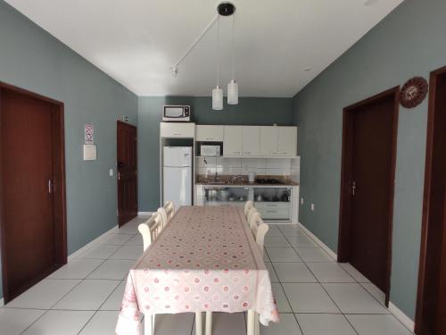 a dining room with a table and a kitchen at Apto próximo a Lagoa do Ibiraquera in Garopaba