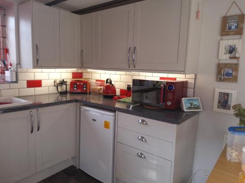 a kitchen with white cabinets and a red microwave at Number Five in Abbotsbury