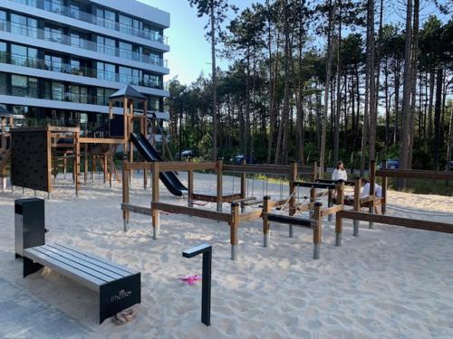 een park met een speeltuin met banken en een glijbaan bij SHELLTER Apartament Blue Dune-Rogowo in Rogowo