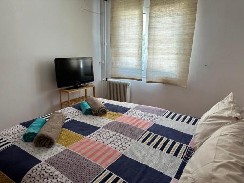 a bedroom with a quilt on a bed with a tv at Goldy Centre Home in Rethymno Town