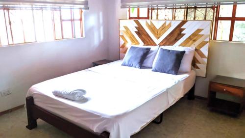 Casa de descanso acacias meta في اكاثياس: غرفة نوم مع سرير أبيض كبير مع وسائد زرقاء