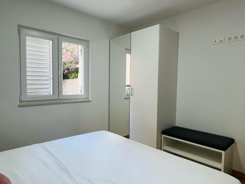a bedroom with a white bed and a window at Apartmani AViS in Selce