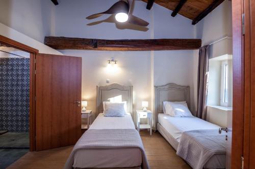 a bedroom with two beds and a ceiling fan at Marcora's Historical Estate in Strongylí